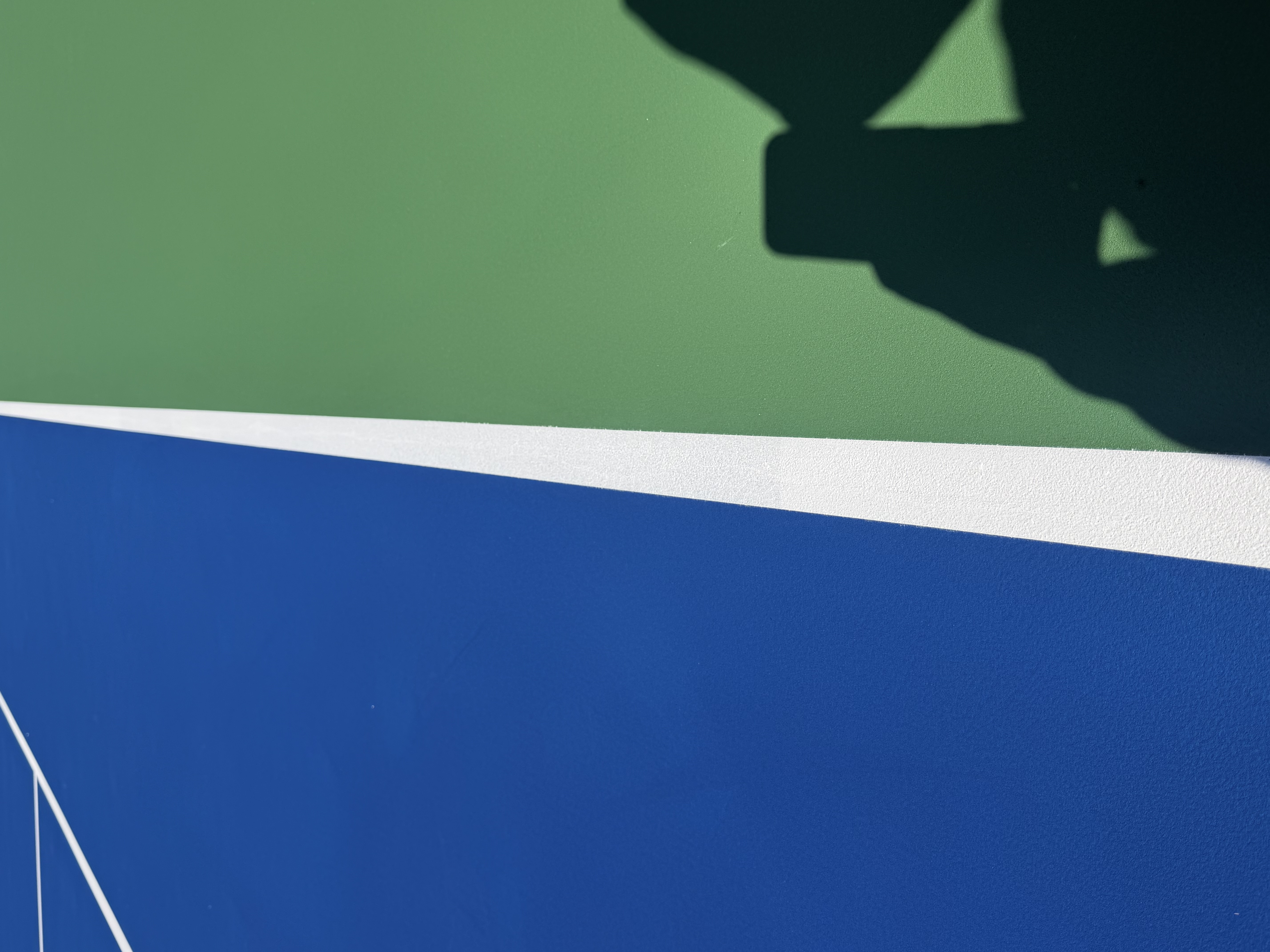 Fresh acrylic court surface detail showing blue and green zones by Xio Construction